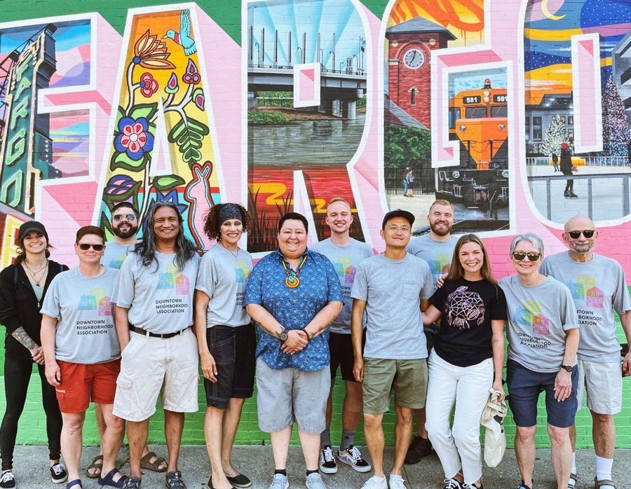 Fargo-Moorhead region - Get involved: A group of people standing in front of a colorful mural.