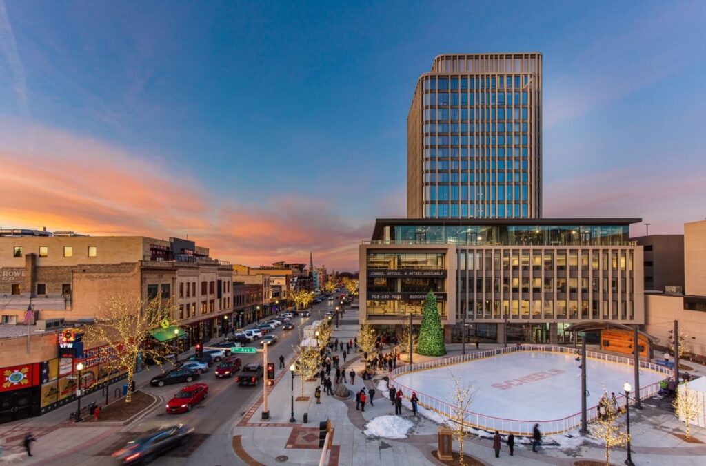 An ice rink in the middle of a city at sunset.